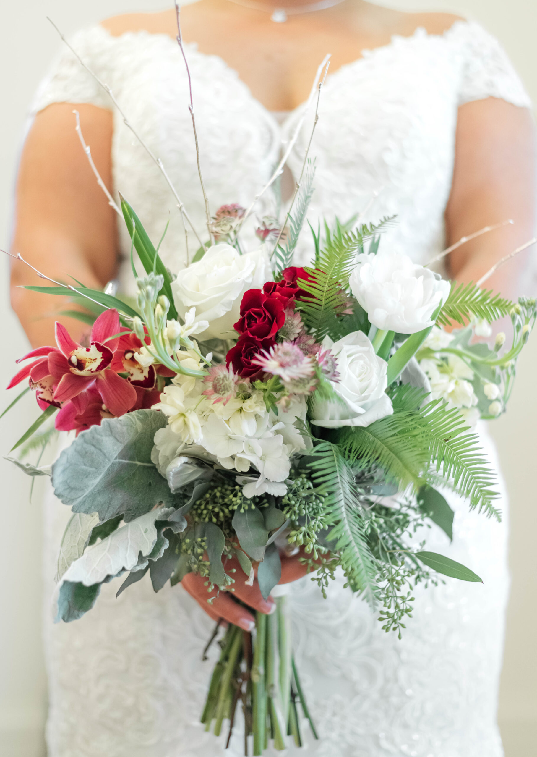 A bride holding a bouquet against her wedding dress.